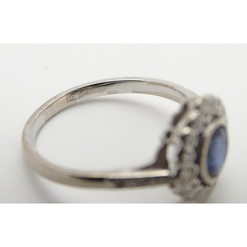 450 - An 18ct white gold ring set with central sapphire bordered by diamonds