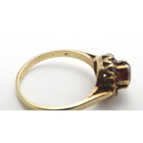 453 - A 9ct gold ring set with garnet cluster ring, the central  stone surrounded by twelve smaller stones... 