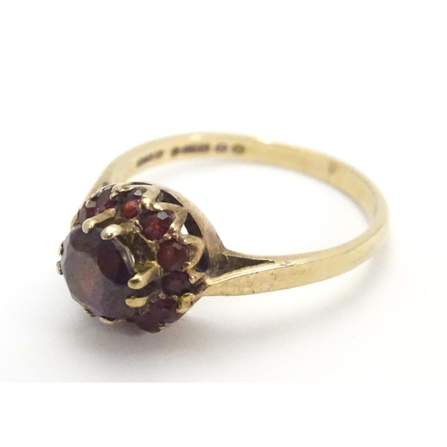 453 - A 9ct gold ring set with garnet cluster ring, the central  stone surrounded by twelve smaller stones... 