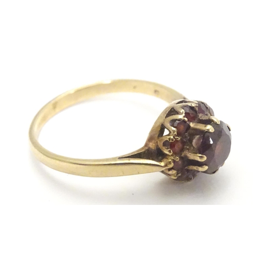 453 - A 9ct gold ring set with garnet cluster ring, the central  stone surrounded by twelve smaller stones... 