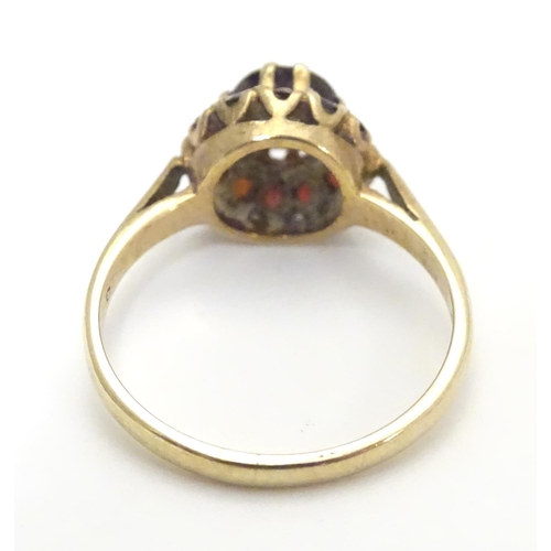 453 - A 9ct gold ring set with garnet cluster ring, the central  stone surrounded by twelve smaller stones... 