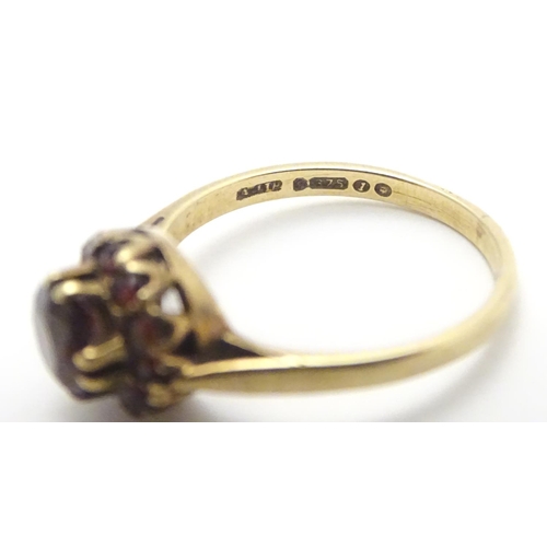 453 - A 9ct gold ring set with garnet cluster ring, the central  stone surrounded by twelve smaller stones... 