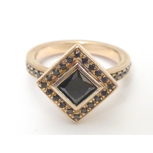 465 - A 14ct rose gold ring set with central princess cut black diamond bordered by round brilliant cut di... 