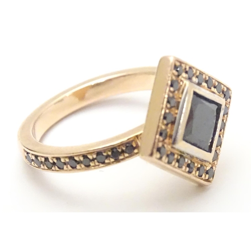 465 - A 14ct rose gold ring set with central princess cut black diamond bordered by round brilliant cut di... 