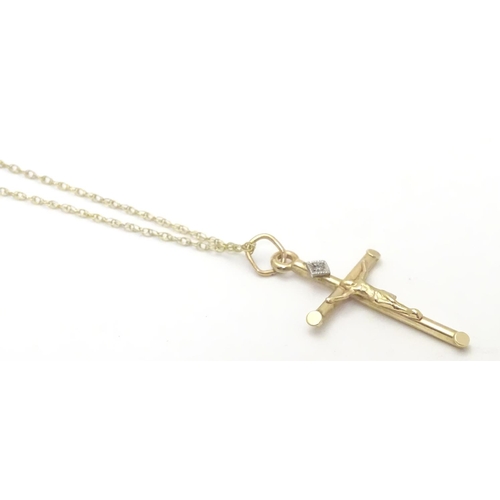 479 - A 9ct gold pendant formed as a crucifix set with single diamond on a 18