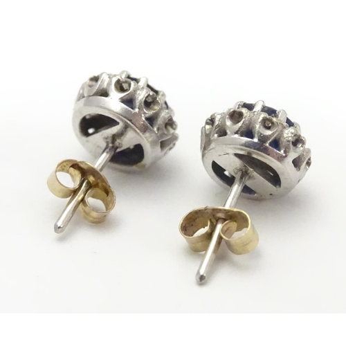 481 - A pair of 9ct white gold stud earrings set with central blue spinel bordered by white stones in a cl... 