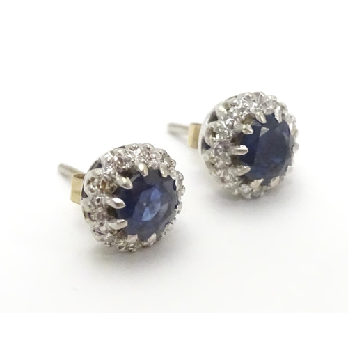 481 - A pair of 9ct white gold stud earrings set with central blue spinel bordered by white stones in a cl... 