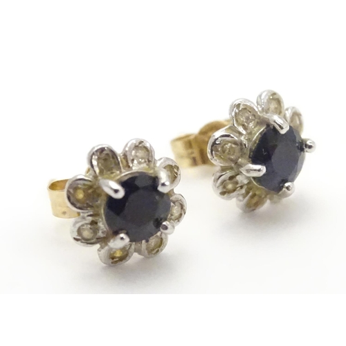 482 - A pair of 9ct gold stud earrings set with central blue stone bordered by chip set diamonds. Approx. ... 