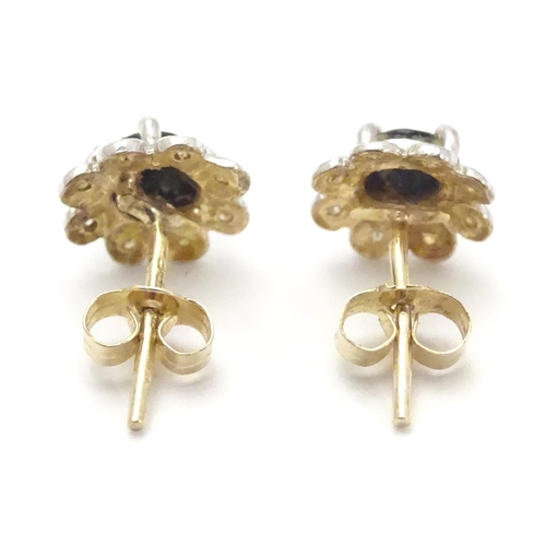 482 - A pair of 9ct gold stud earrings set with central blue stone bordered by chip set diamonds. Approx. ... 