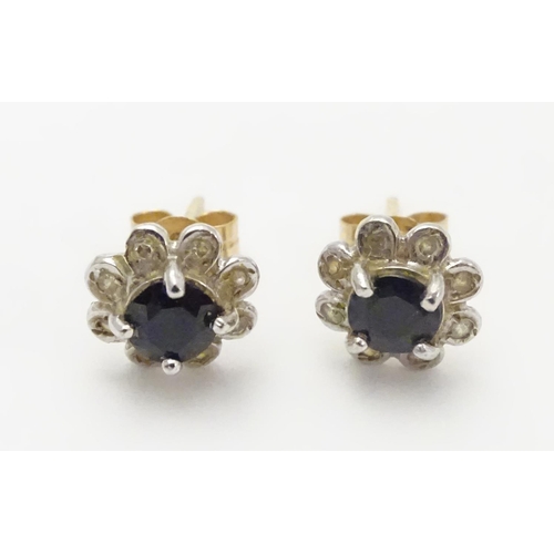 482 - A pair of 9ct gold stud earrings set with central blue stone bordered by chip set diamonds. Approx. ... 