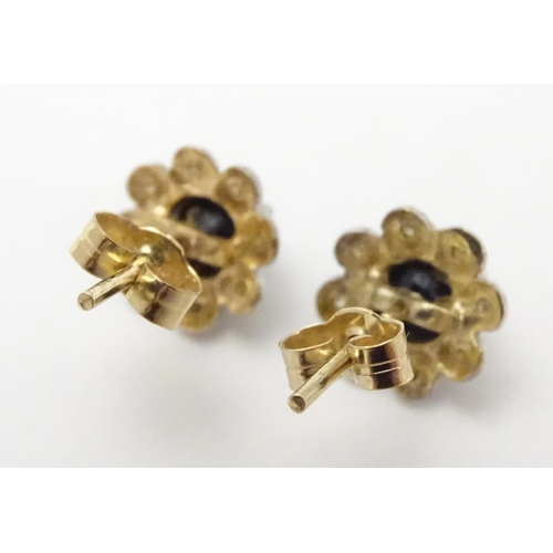 482 - A pair of 9ct gold stud earrings set with central blue stone bordered by chip set diamonds. Approx. ... 