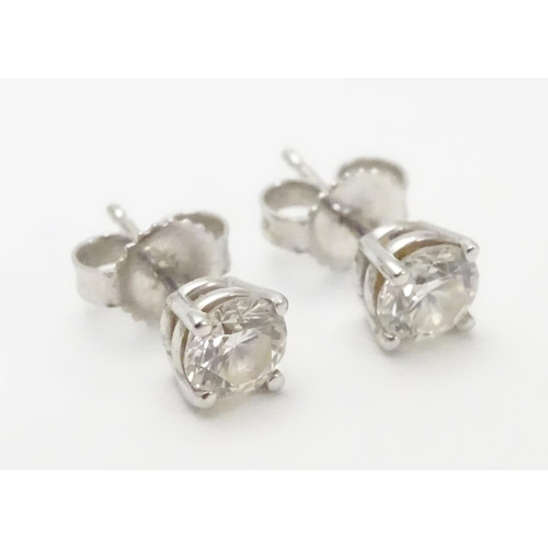 483 - A pair of white gold stud earrings set with diamond solitaires. The diamond approximately 1/8