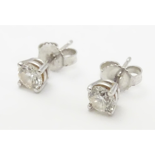 483 - A pair of white gold stud earrings set with diamond solitaires. The diamond approximately 1/8