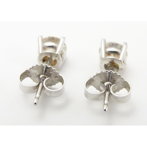 483 - A pair of white gold stud earrings set with diamond solitaires. The diamond approximately 1/8