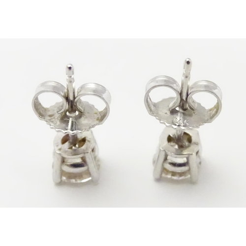 483 - A pair of white gold stud earrings set with diamond solitaires. The diamond approximately 1/8