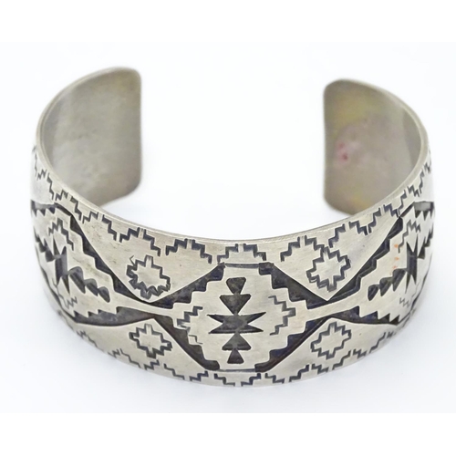 484 - A North American bangle formed bracelet with incised geometric decoration. Marked Sterling