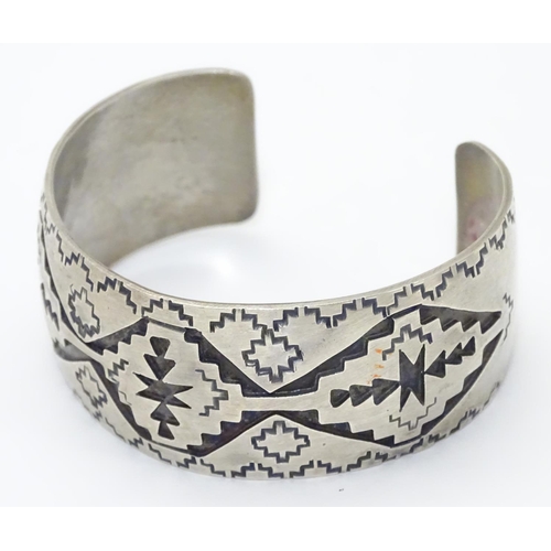 484 - A North American bangle formed bracelet with incised geometric decoration. Marked Sterling