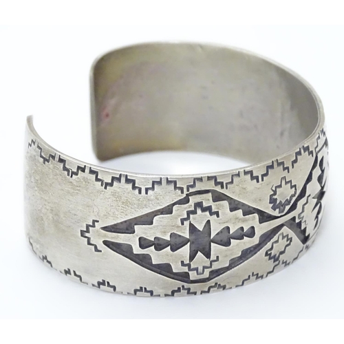 484 - A North American bangle formed bracelet with incised geometric decoration. Marked Sterling