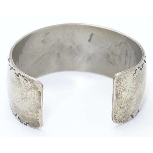 484 - A North American bangle formed bracelet with incised geometric decoration. Marked Sterling