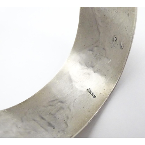 484 - A North American bangle formed bracelet with incised geometric decoration. Marked Sterling