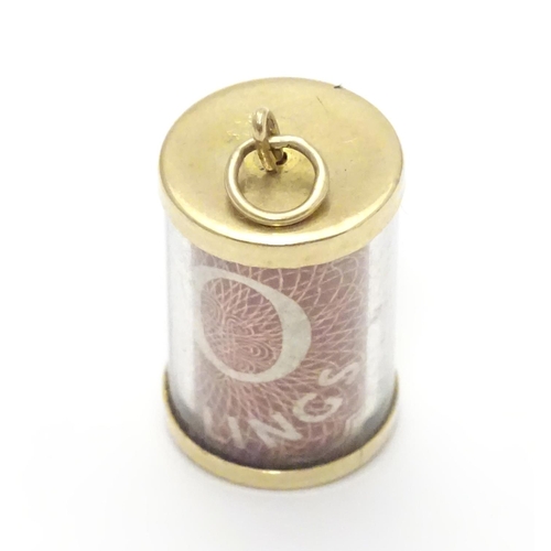 495 - A 9ct gold novelty pendant / charm of cylindrical form with rolled 10 shilling note to centre. Appro... 