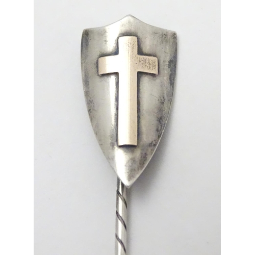 496 - A hallmarked silver stick pin surmounted by a shield cartouche with cross decoration. The whole appr... 