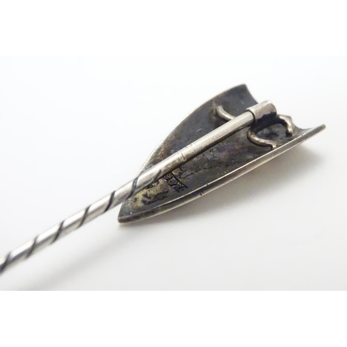 496 - A hallmarked silver stick pin surmounted by a shield cartouche with cross decoration. The whole appr... 