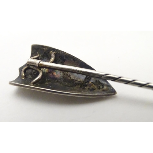 496 - A hallmarked silver stick pin surmounted by a shield cartouche with cross decoration. The whole appr... 