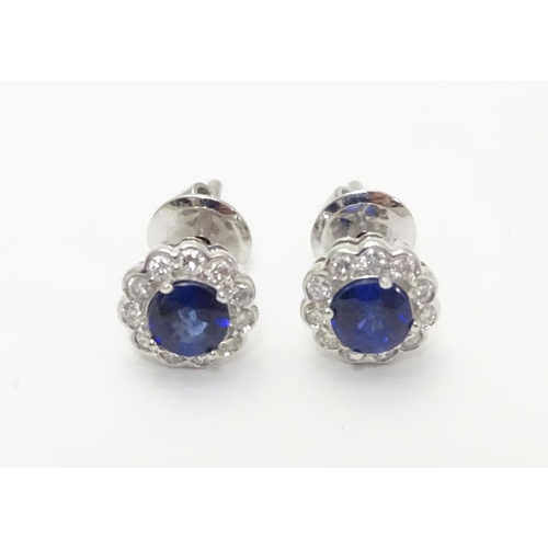 497 - A pair of 18ct gold stud earrings set with central sapphire bordered by diamonds. Approx. 1/4