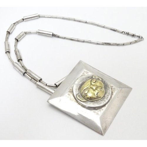 499 - An unusual silver necklace with large square pendant with hammered decoration and silver gilt face t... 