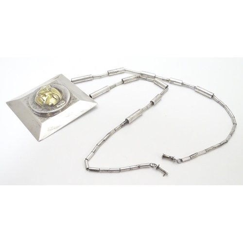 499 - An unusual silver necklace with large square pendant with hammered decoration and silver gilt face t... 