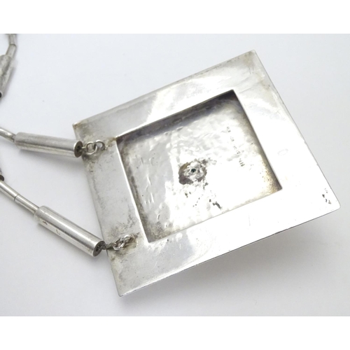 499 - An unusual silver necklace with large square pendant with hammered decoration and silver gilt face t... 