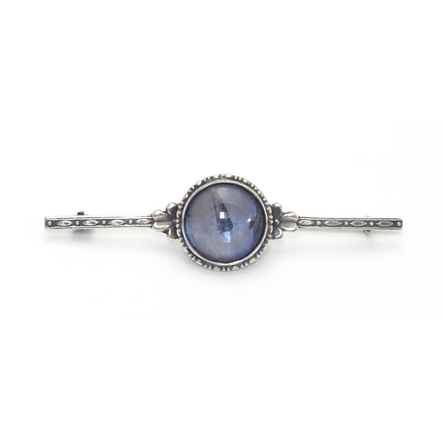 505 - A silver bar brooch, the central circular section mounted with butterfly wing detail behind glass. M... 