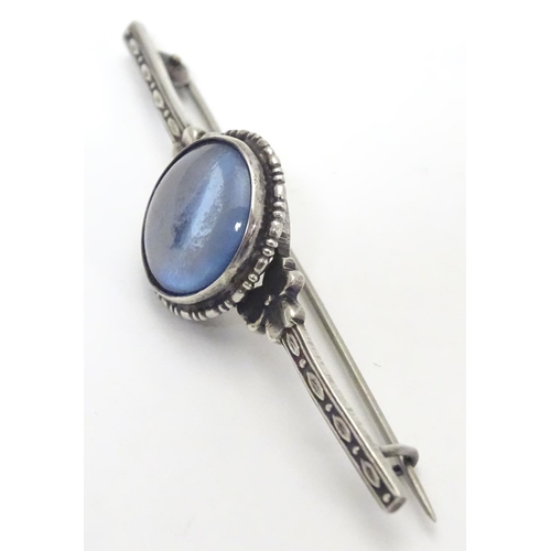 505 - A silver bar brooch, the central circular section mounted with butterfly wing detail behind glass. M... 