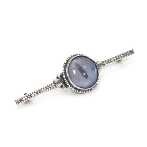 505 - A silver bar brooch, the central circular section mounted with butterfly wing detail behind glass. M... 