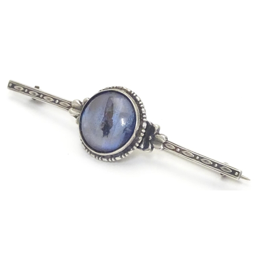 505 - A silver bar brooch, the central circular section mounted with butterfly wing detail behind glass. M... 