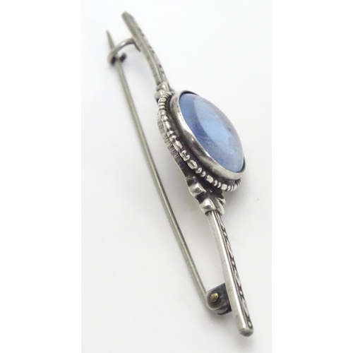 505 - A silver bar brooch, the central circular section mounted with butterfly wing detail behind glass. M... 