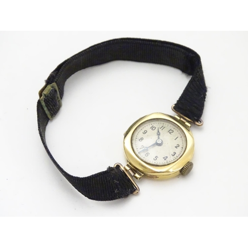 558 - An early 20thC Ladies' wrist watch , with fabric strap and 18ct gold case