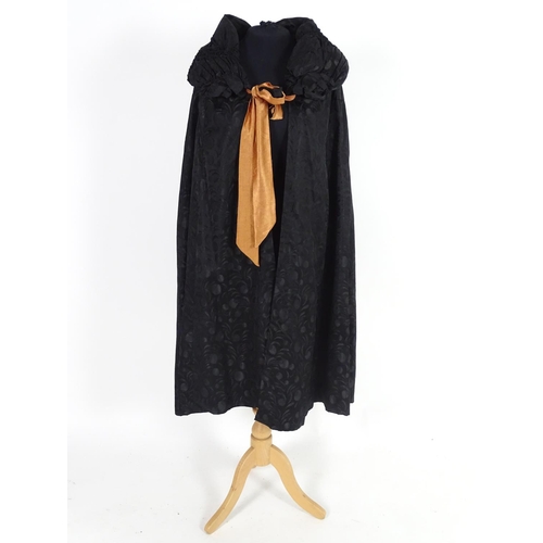 730 - A bespoke vintage ladies black evening cape, with padded collar, tie to neck. Bronze/orange lining. ... 