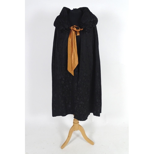 730 - A bespoke vintage ladies black evening cape, with padded collar, tie to neck. Bronze/orange lining. ... 