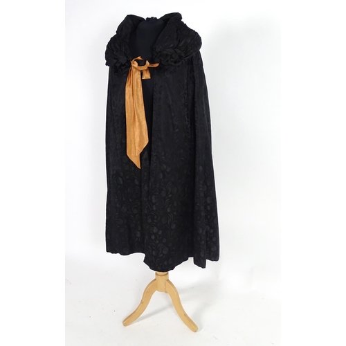 730 - A bespoke vintage ladies black evening cape, with padded collar, tie to neck. Bronze/orange lining. ... 