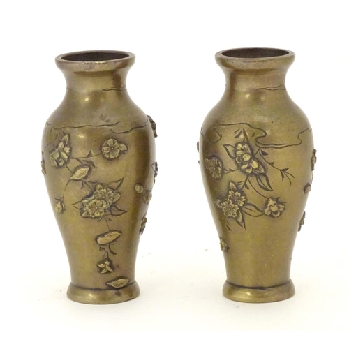 832 - A pair of late 19th / early 20thC miniature brass vases with engraved and relief decoration depictin... 