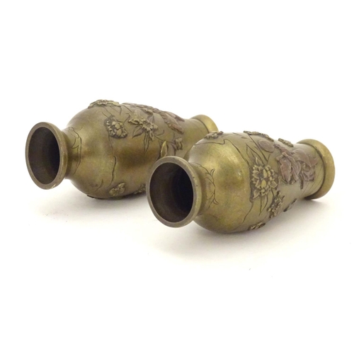 832 - A pair of late 19th / early 20thC miniature brass vases with engraved and relief decoration depictin... 