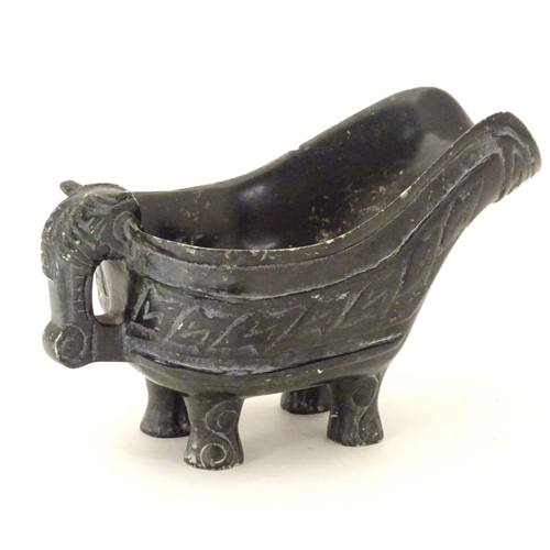 839 - An Oriental carved stone vessel with a pouring spout, beast formed handle and four feet. The side in... 