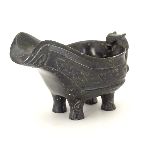 839 - An Oriental carved stone vessel with a pouring spout, beast formed handle and four feet. The side in... 