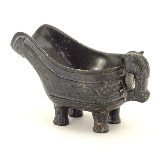 839 - An Oriental carved stone vessel with a pouring spout, beast formed handle and four feet. The side in... 