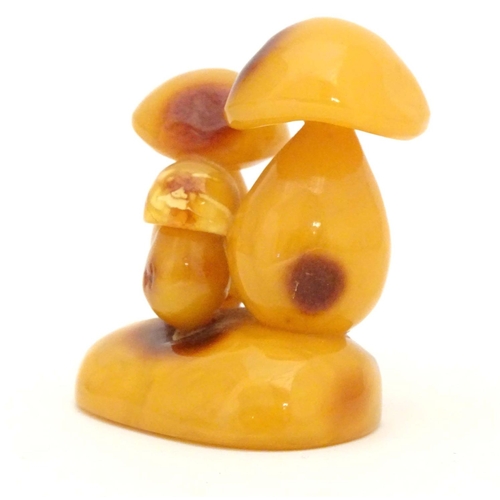 962 - A late 19th / early 20thC amber carving modelled as a group of three toadstools. Approx. 2