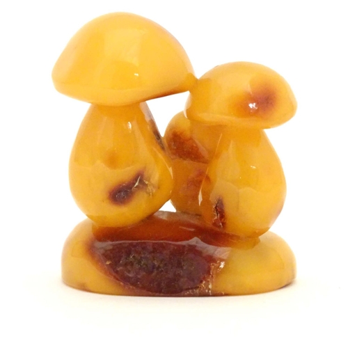 962 - A late 19th / early 20thC amber carving modelled as a group of three toadstools. Approx. 2