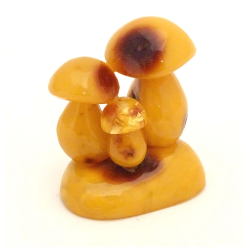 962 - A late 19th / early 20thC amber carving modelled as a group of three toadstools. Approx. 2