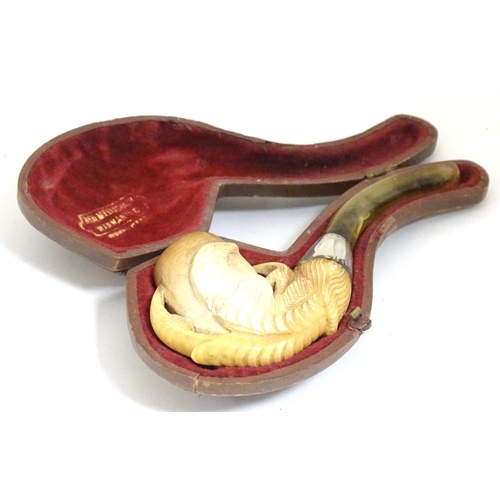 980 - An early 20thC cased carved meerschaum pipe, the bowl formed as an eagle talon, joined to the amber ... 